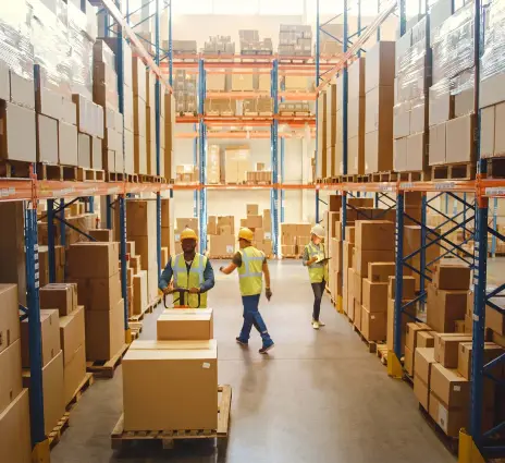 Warehouse workers in safety vests managing inventory in tall storage racks