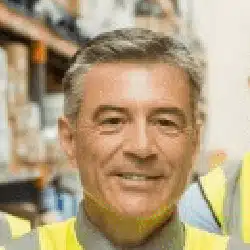Professional businessman in high-visibility vest smiling in warehouse setting