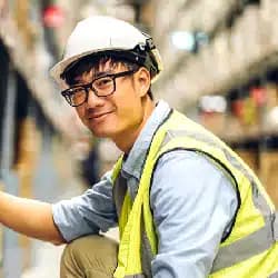 Smiling construction worker in hard hat and safety vest at industrial site