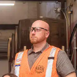 Construction worker in orange safety vest and hard hat at industrial worksite