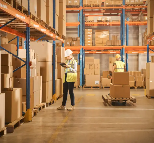 Two warehouse workers in safety vests managing inventory in modern distribution center