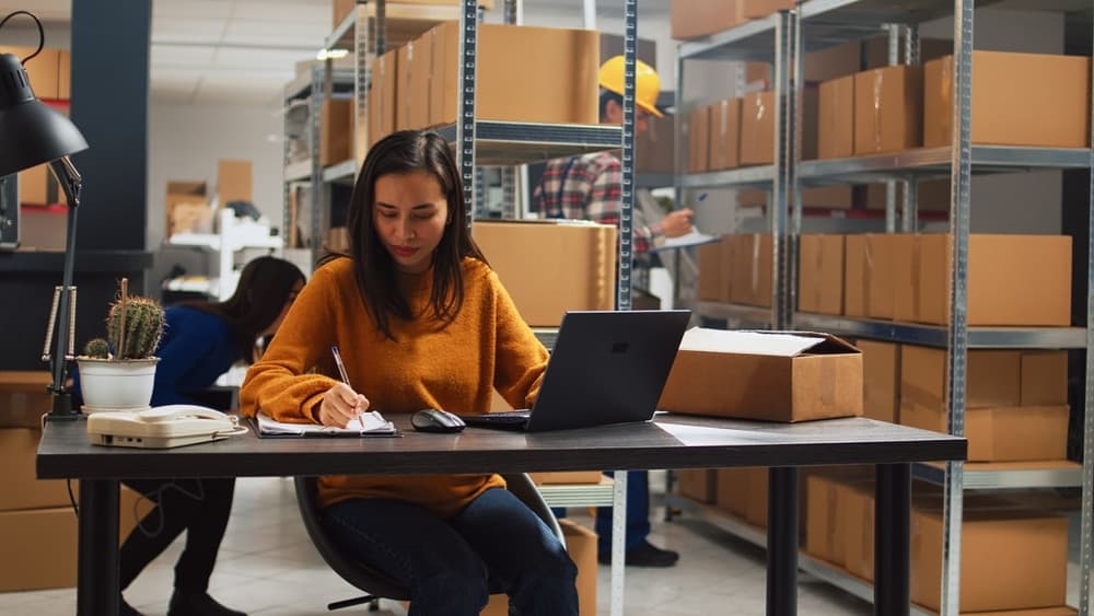 warehouse worker at a desk looking at computer