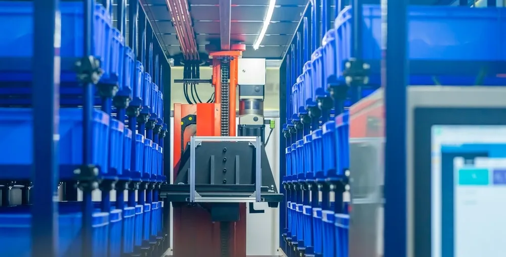 Automated storage and retrieval system robot navigating between blue storage shelves in warehouse