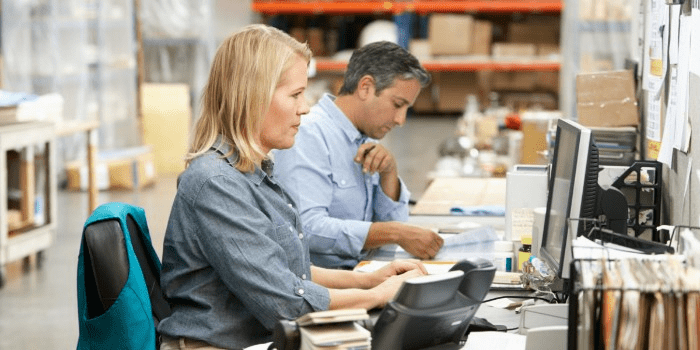 warehouse worker looking through reports on a computer screen