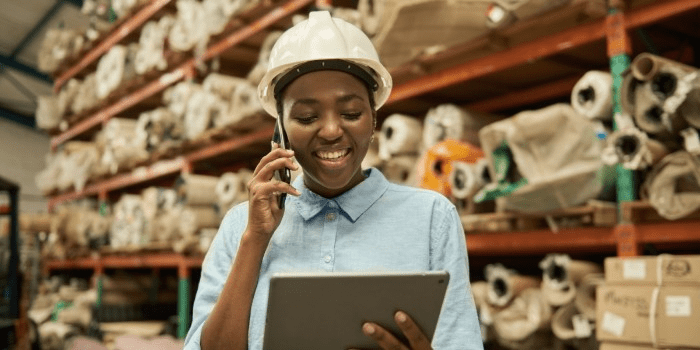 smiling african american warehouse worker holding manufacturing inventory management tablet