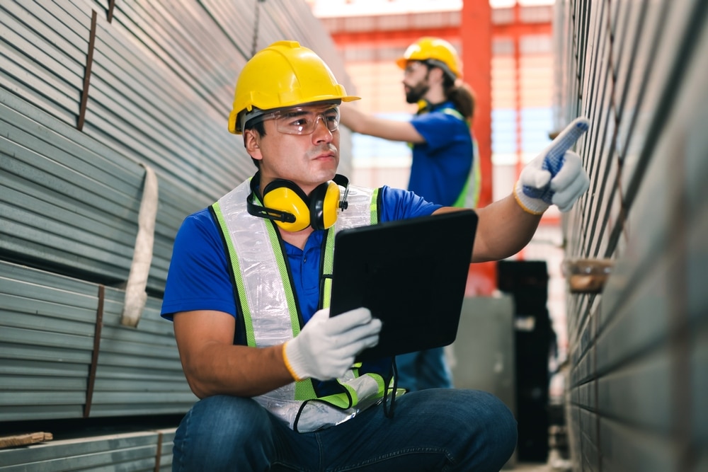 male worker using manufacturing inventory management software to count metal pieces