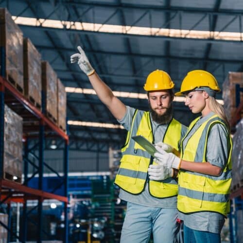 warehouse workers using manufacturing inventory management software tablet