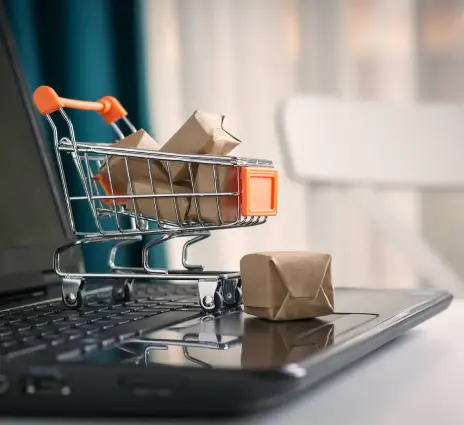 small shopping cart with packages sitting on laptop computer