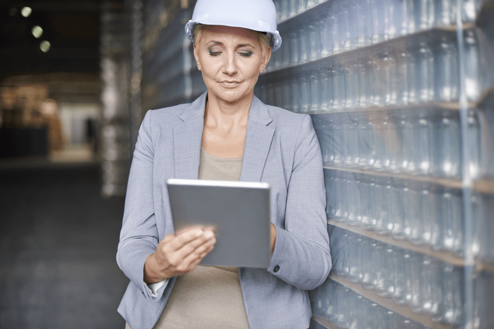 woman looking at a tablet in a warehouse storing glass bottles