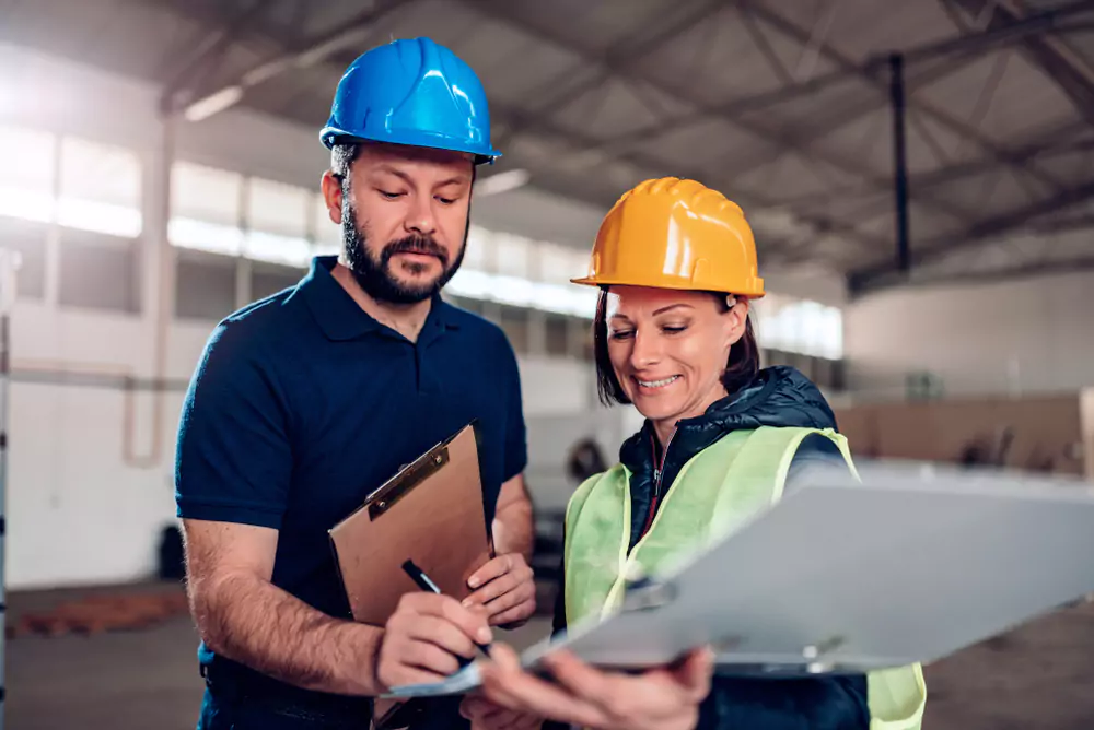 two warehouse workers looking at a document and one of them signing it