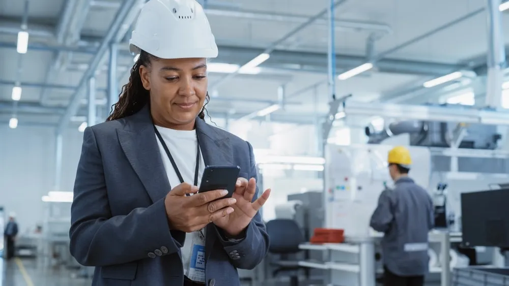 female manufacturing manager using master production schedule software on mobile device
