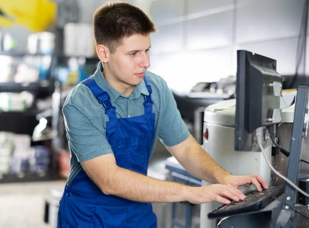 Warehouse worker in blue uniform using computer system for pharmaceutical inventory management