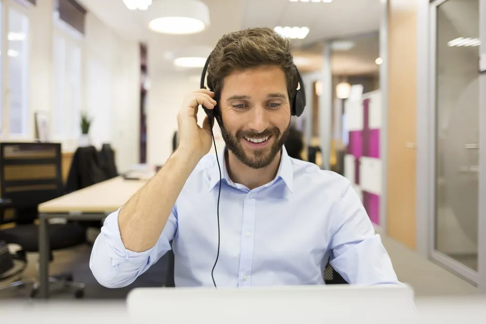 Smiling businessman wearing headset in modern office discussing lean manufacturing principles