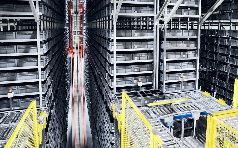 Automated storage and retrieval system with robotic machinery moving through warehouse aisles