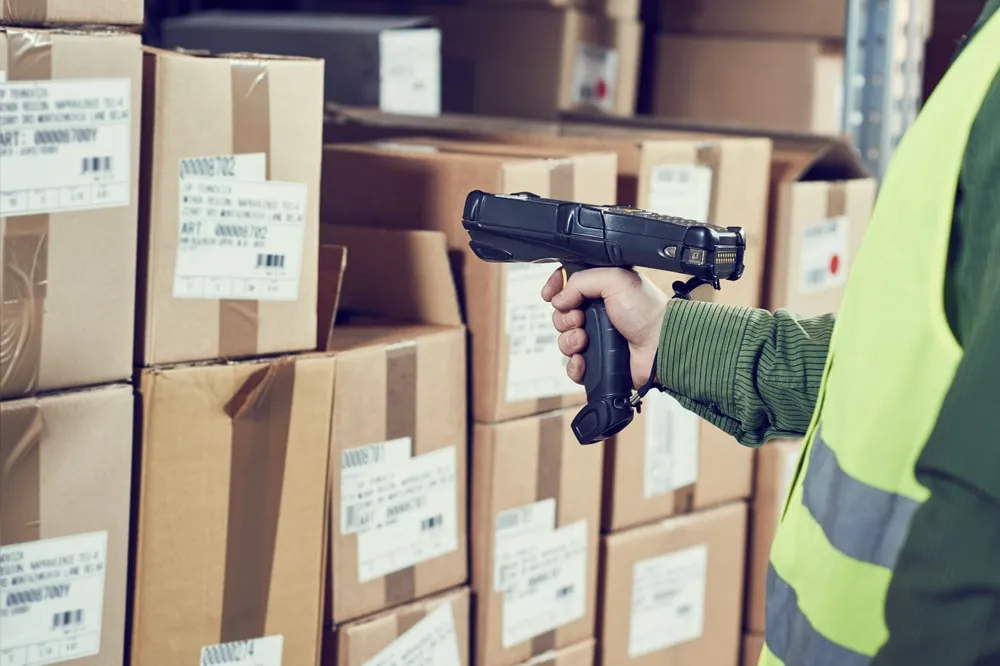 Warehouse worker using handheld barcode scanner to track inventory on shelves